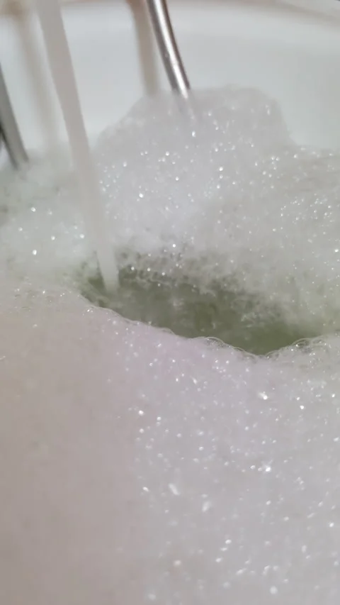 Vertical video close-up water pouring from faucet into bathtub creating foam Stock Footage 313538057