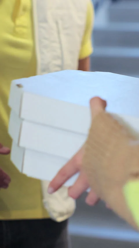 Vertical video. Close up woman opens doors and meets pizza delivery man Stockbeeldmateriaal 344372458