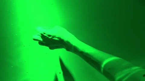 Vertical video close-up of womans hand under green water performs chaotic smooth Stock Footage 312450794