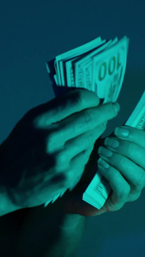 Vertical video. Close-up of a woman's hands organizing a stack of hundred-dollar Stock Footage 296360260