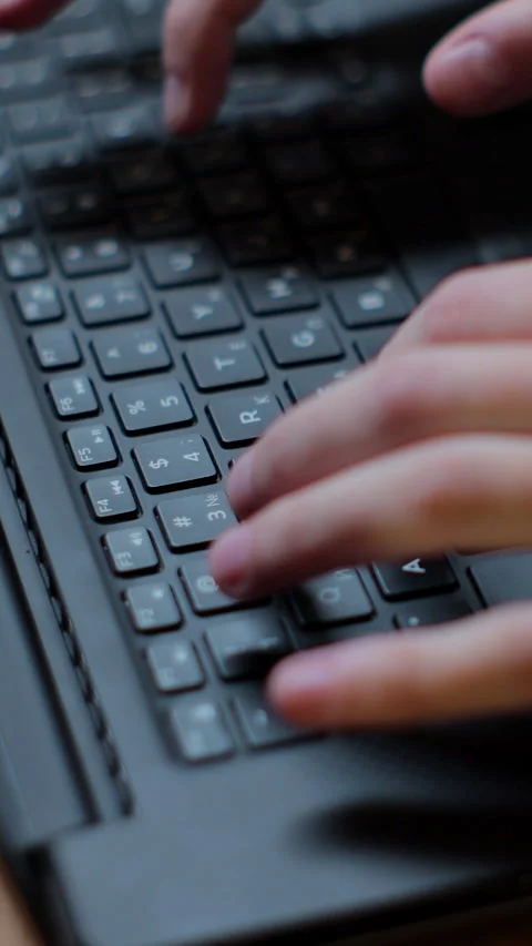 Vertical video. Close up Young man working in a cafe, typing on laptop 動画素材 345235416