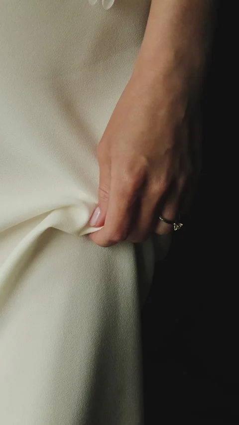 Vertical video. Closeup bride hand gripping silk dress, wedding ring visible on Stock Footage 322051320
