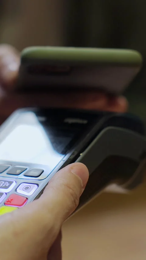 Vertical video. Closeup man hand paying with mobile phone over pos terminal Stock Footage 345240553