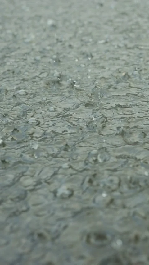 Vertical video, Closeup of raindrops falling into puddle on the pavement. Heavy Stock Footage 205118296