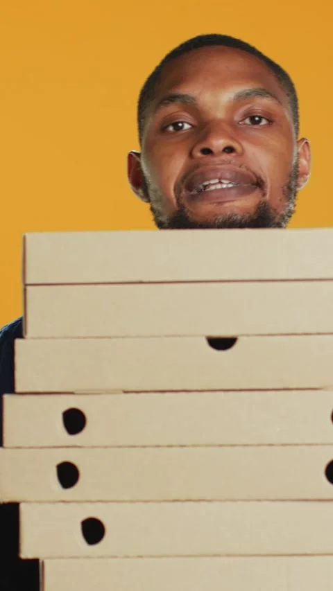 Vertical Video Clumsy deliveryman dropping a huge stack of pizza boxes in studio Video stock 275559756