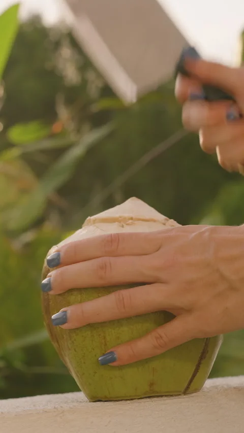 Vertical video. Coconut Juice Splashing in Slow Motion as Knife Hits Fruit on Stock Footage 315564439