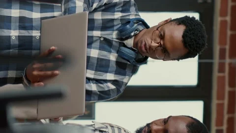 Vertical video Coders talking about algorithms holding laptop pointing at sorce Stock Footage 194147216