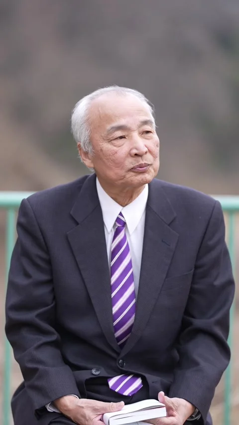 A vertical video in a cold natural park in Japan in March. A man in his 70s, in Stock Footage 307659331