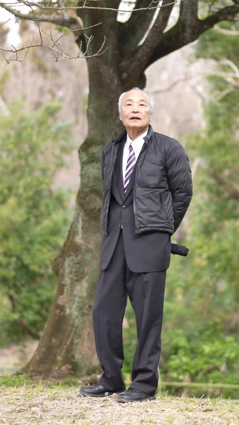 A vertical video in a cold natural park in Japan in March. A man in his 70s, in 스톡 동영상 307659900
