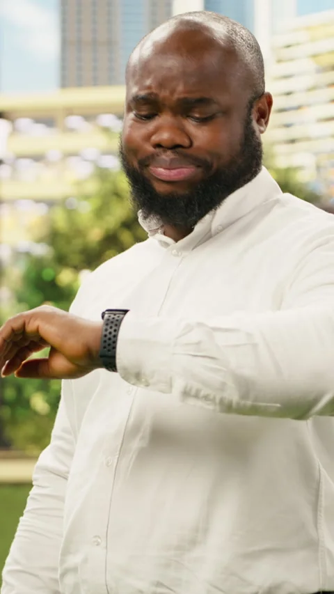 Vertical Video Concerned businessman checking time on smartwatch while standing Vídeos de archivo 344378781