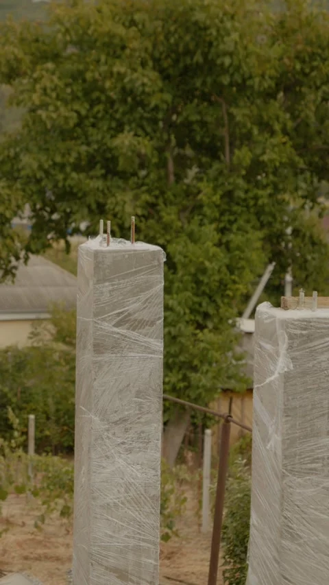 Vertical video Concrete columns wrapped in foil for moisture retention during Stock Footage 327603995