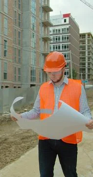 Vertical video. Construction professional analyzing project plan at building  Stock Photos