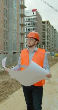 Vertical video. Construction professional analyzing project plan at building  Stock Photos