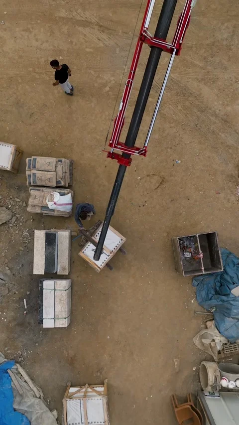 Vertical Video: Construction Unveiled - Aerial View of Crane Unloading Cargo and Stock Footage 245192283
