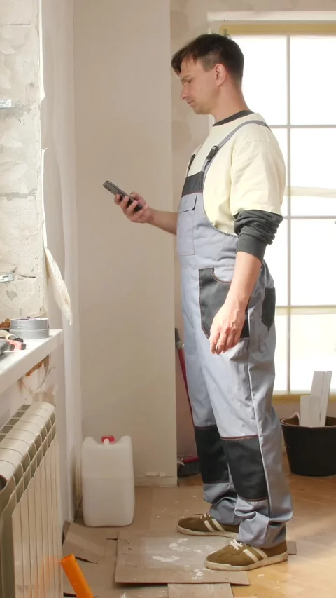 Vertical video construction worker using smartphone during renovation break Stock Footage 312985980