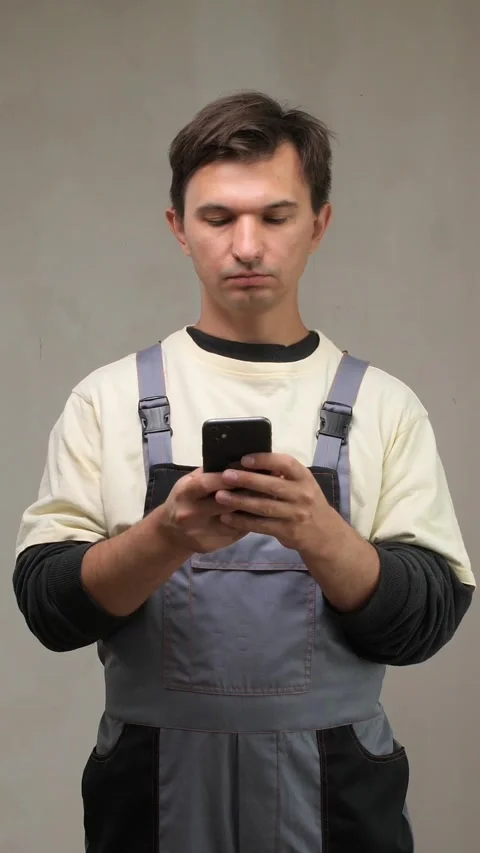 Vertical video Construction worker using smartphone in unfinished room Stock Footage 313299673