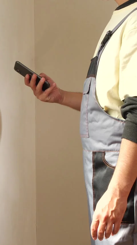 Vertical video construction worker using smartphone on site managing project Stock Footage 314082576