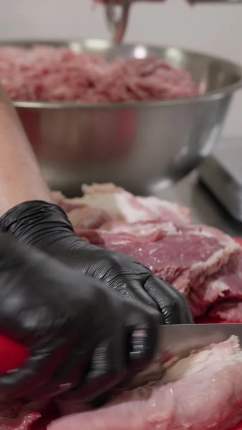 Vertical video. Cook uses knife to cut meat on table in kitchen of production Video stock 323066559