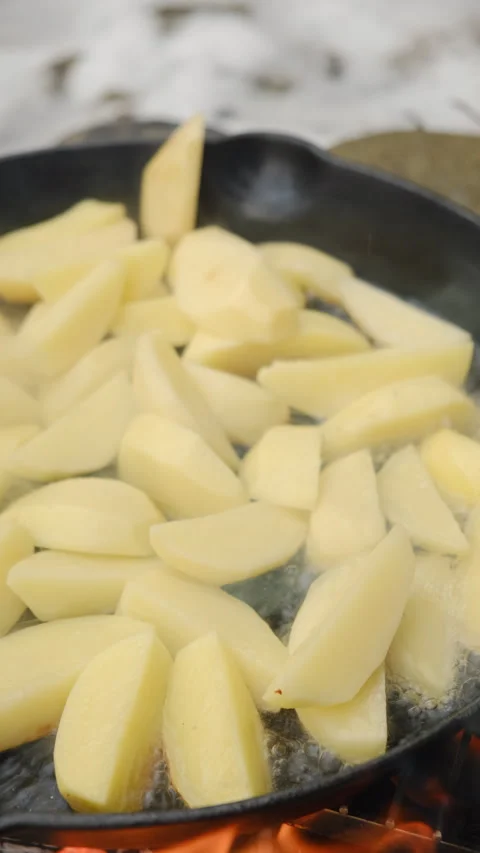 Vertical video of cooking fried potatoes in frying black pan at winter day Stock Footage 297960898