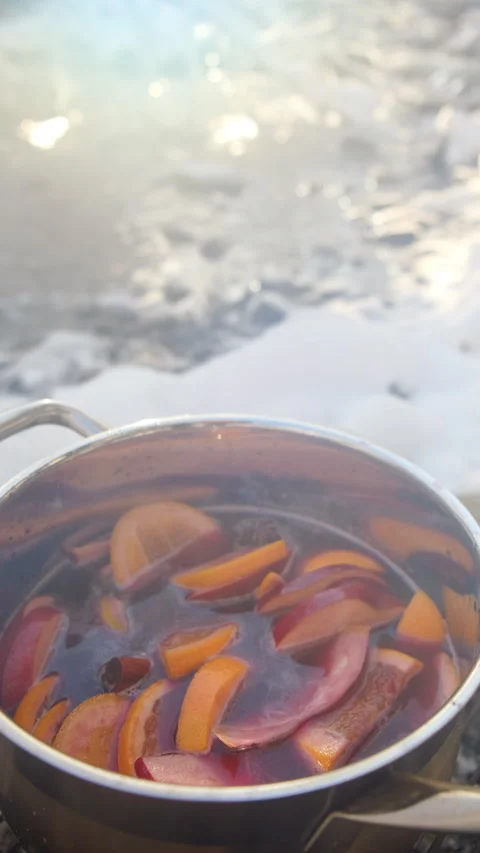 Vertical video of cooking mulled wine on bonfire at near mountains river Stock Footage 300942140
