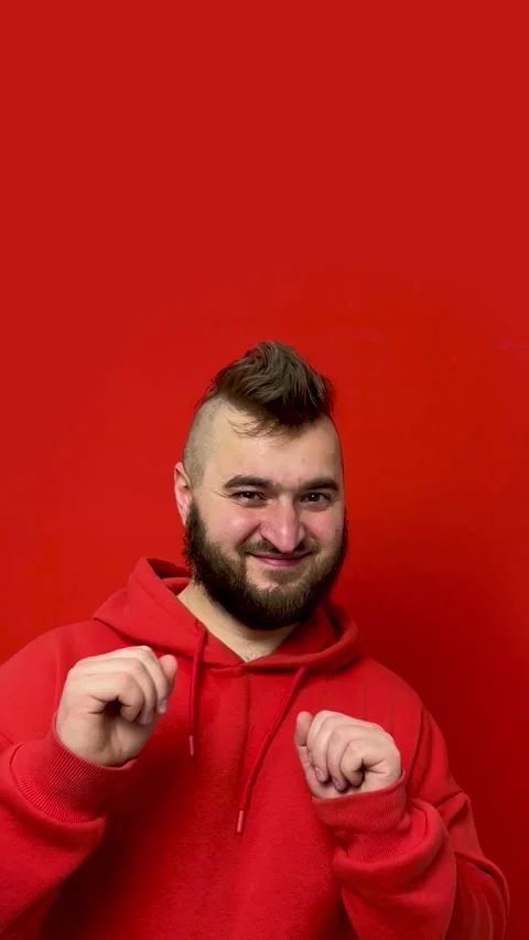 Vertical video with copyspace. Young man with beard dances on red background Stock Footage 274235502