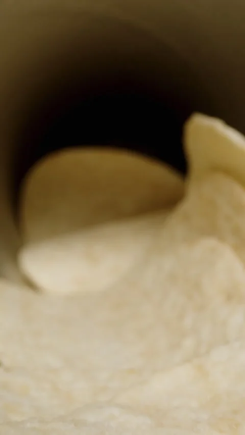 Vertical video. Corn chips, hyperbolic paraboloid in shape, are scattered from a Video stock 260975467
