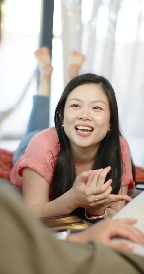 Vertical video: Couple in bed, Chinese woman reacting to partner pointing at Stock Footage 345395917