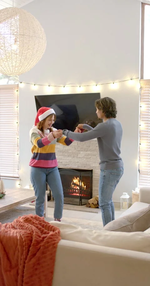 Vertical video: Couple dancing by fireplace man initiating spins woman in Santa Stock Footage 344231796