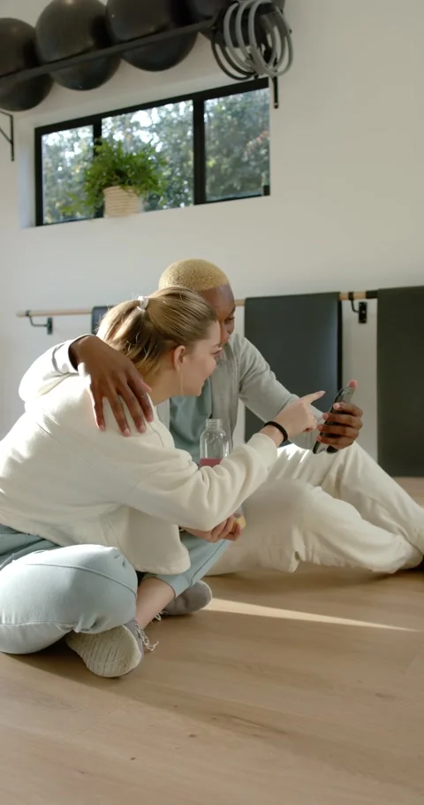 Vertical video: Couple in gym, he holding phone while she tapping and sipping Видео 346735332