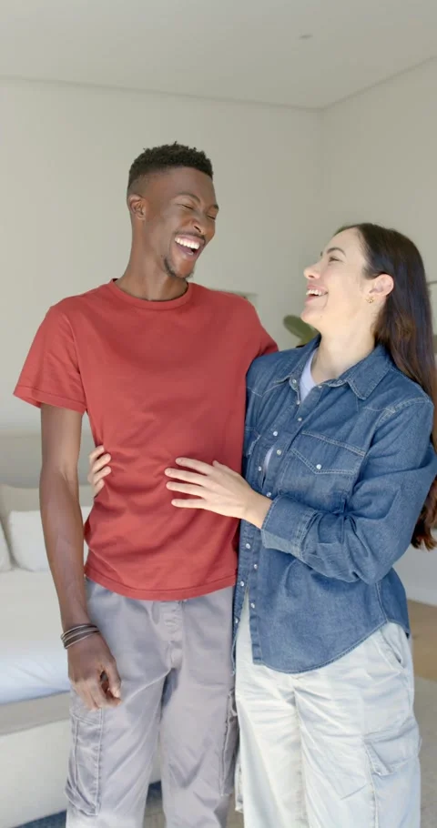 Vertical video: Couple laughing and hugging in bedroom after woman touching man Stock Footage 337259192