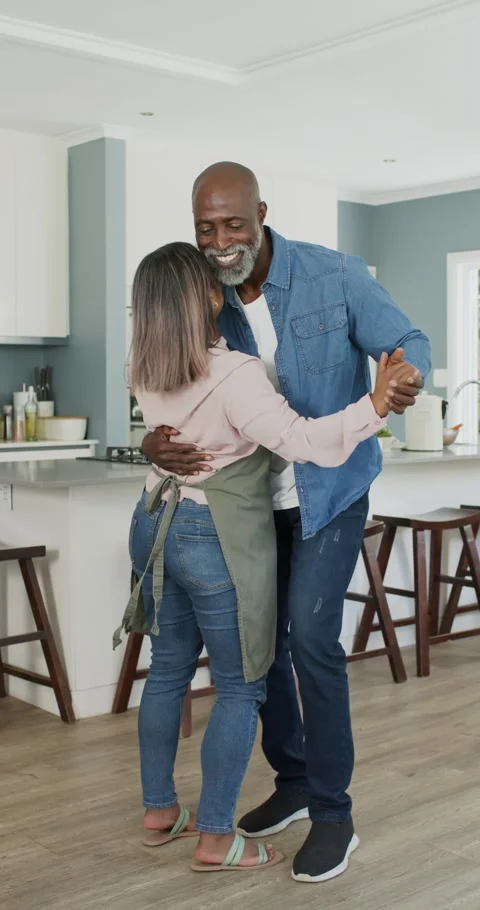 Vertical video: Couple with man taking woman's hand at island, in apron leading Stock Footage 345321253