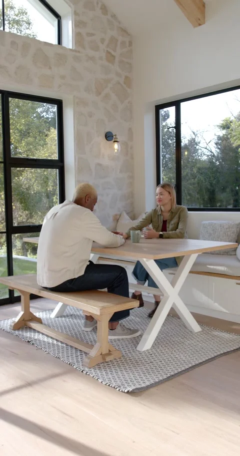 Vertical video: Couple sitting at table locking eyes, connecting, man reaching, Видео 346735352