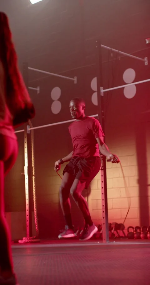 Vertical video: Couple training at gym, African man in red shirt starting jump Stock Footage 339804281