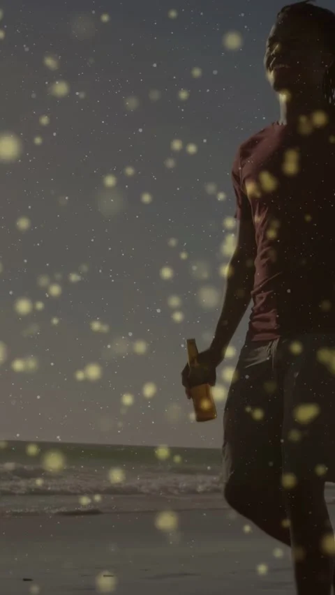 Vertical video: Couple walking beach cam rising revealing bottle gold bokeh over Vídeo Stock 332846334