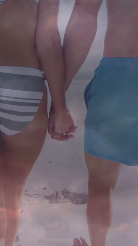 Vertical video: Couple walking on beach, linked hands starting steps pink haze Stock Footage 333896355