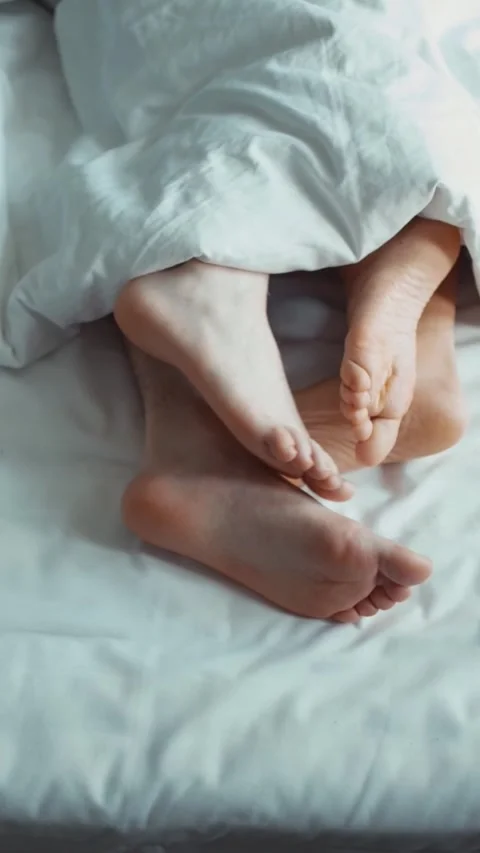 Vertical Video: The couple's legs are on a white sheet and covered with a Stock Footage 303525430