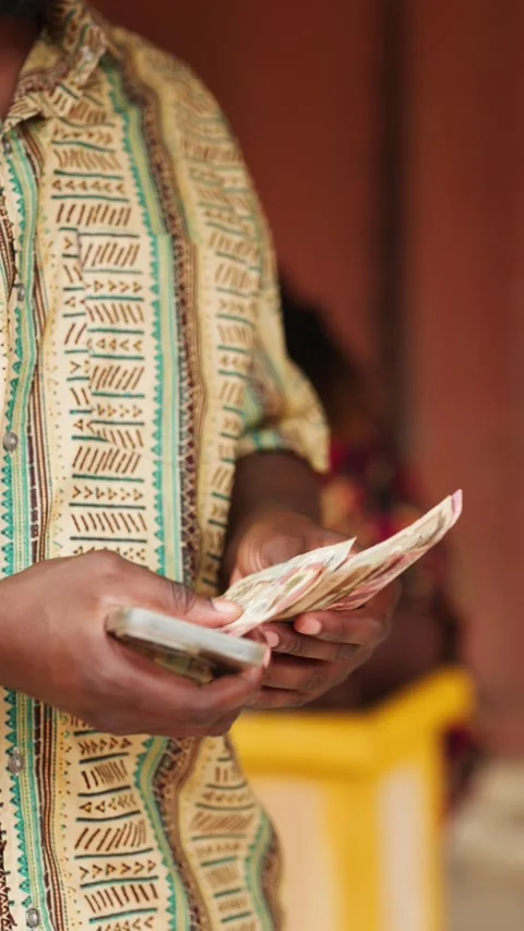 Vertical Video: Customer counts cash after mobile money withdrawal in Africa  Stock Footage 347690219