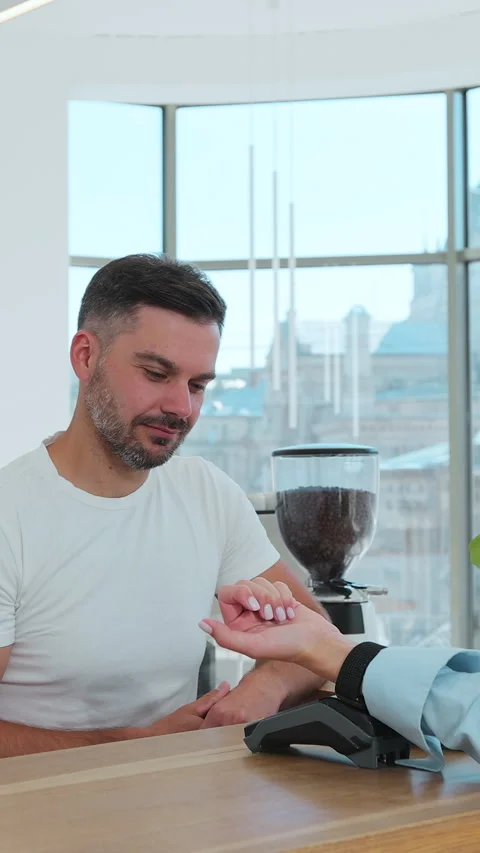 Vertical video. Customer paying with an NFC contactless smartwatch Vídeos de archivo 343770196