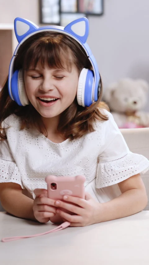 Vertical Video of Cute small kid girl in headphones using funny editing 動画素材 305340900