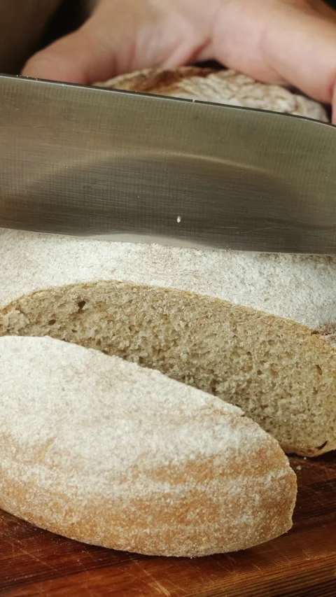 Vertical video. Cutting a rustic country bread Stock Footage 340335587