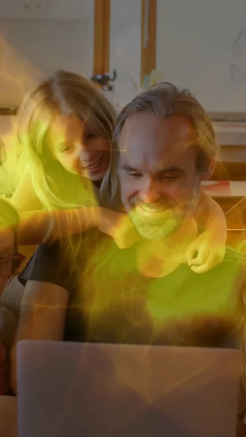 Vertical video: Dad using laptop on sofa, girl climbing onto back viewing Stock Footage 329912886