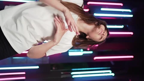 Vertical video - dancer in neon light. Beautiful young woman dancing and having Stock Footage 145193176
