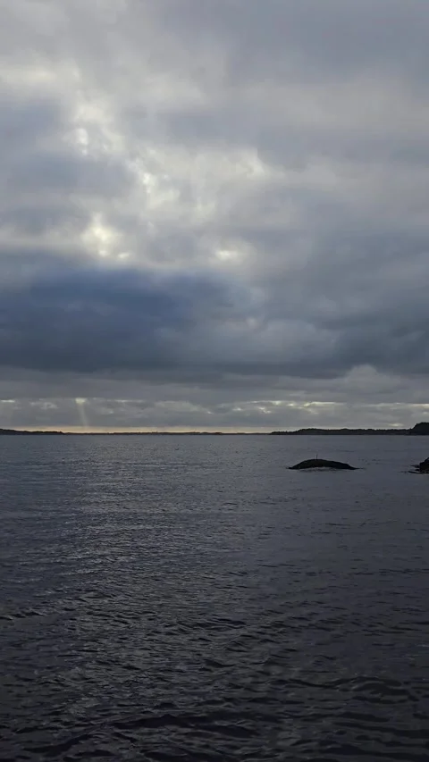 Vertical video of dark ocean waves with dramatic sunbeams through clouds Stock Footage 345168155