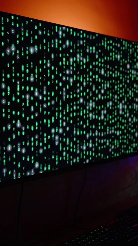 Vertical video. Dark Room with Computer Setup, Large Monitor Displaying Green Stock Footage 281460270