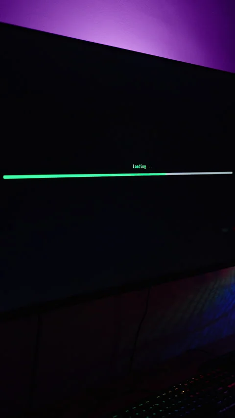 Vertical video. Dark Room with Computer Setup, Monitor Showing Green Loading Bar Stock Footage 281461354