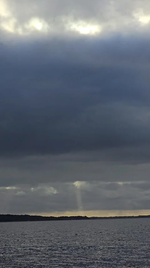 Vertical video of dark stormy ocean waves with dramatic sunbeams through clouds Stock Footage 345168162