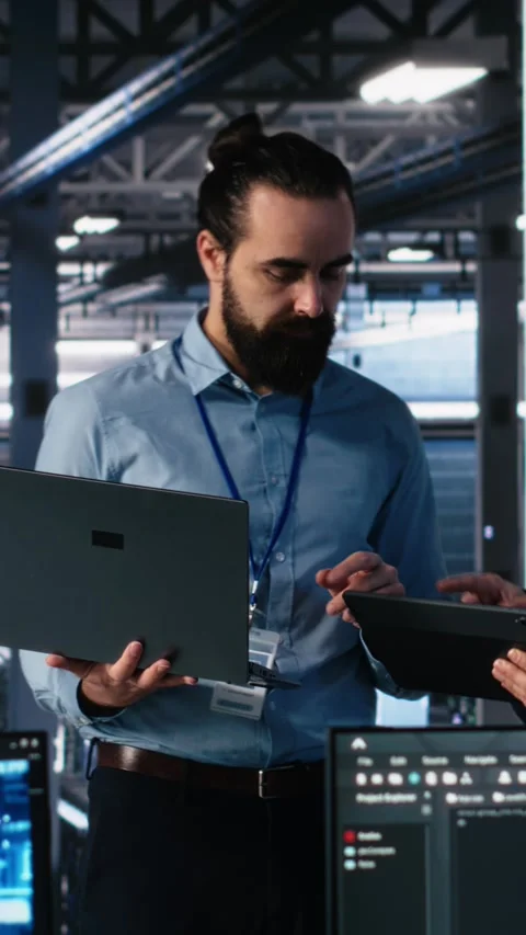 Vertical video Data center manager supervising work done by programmers on Stock Footage 313507873