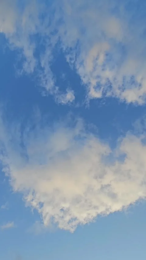 Vertical video of deep blue sky with soft white clouds Stock Footage 329783333