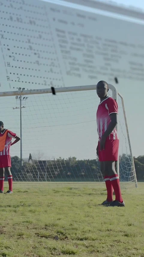 Vertical video: Defender chasing pass, jumping to clear goal while code overlay Stock Footage 333541886