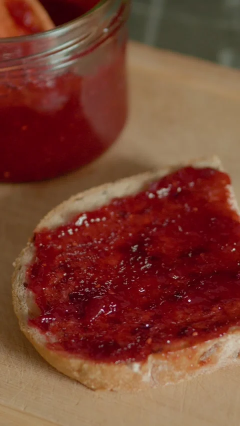 Vertical video Delicious slice of bread topped with raspberry jam on a chopping Stock Footage 323363775